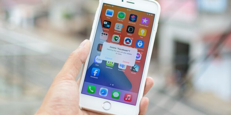 An image of a person holding a smartphone while the screen shows the action to permanently delete their Facebook account.